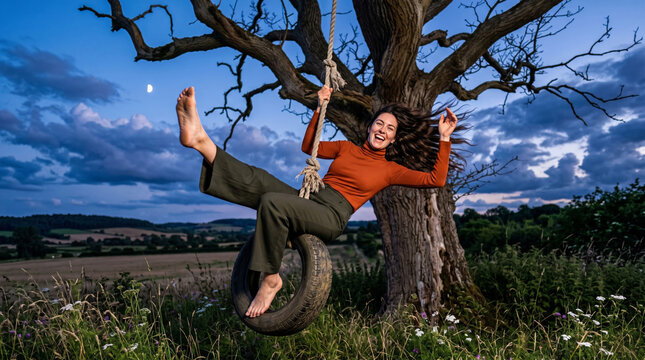 Joyful Woman Swinging on Tire Swing Under Moonlit Evening Sky