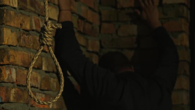 A nervous man on the background of a rope with a noose for suicide. A man on the verge of death. Suicide by hanging. Human psychology. Nervous breakdown.