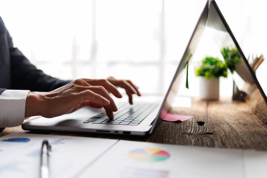 Business professional hands typing on a laptop keyboard, working in a modern office, analyzing financial data and statistics for strategic planning and success