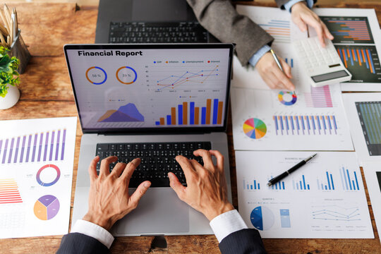 Business people collaborating on financial report, analyzing market data and economic trends, using laptop and calculator for accounting and strategic planning