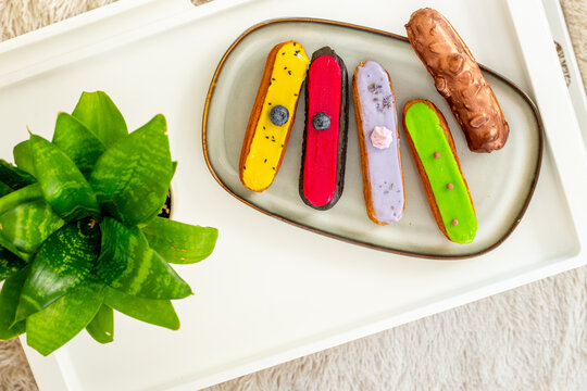 French eclairs served on plate - colorful artisan dessert composition with soft daylight, top view food photography