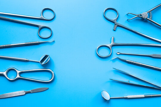 Set of stainless surgical instruments and tools - scalpels, scissors and others - on blue table, top view