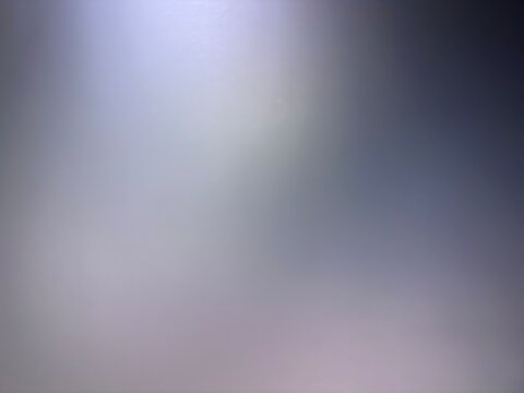 An abstract blurred background featuring a soft gradient transition from cool dark slate blue and dark gray down to subtle muted mauve tones, illuminated by a glowing top spotlight copy space