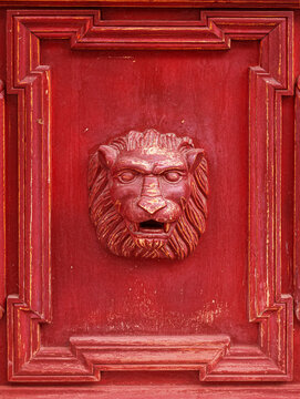 Ornate red door with carved lion head sculpture