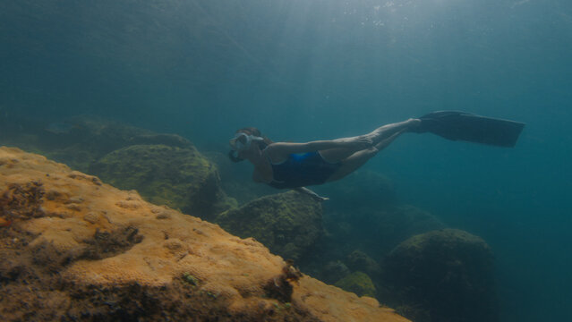 Young slim woman swims underwater, freediving and snorkeling in the sea near the coral reef near the island of Ilha Grande in Brazil