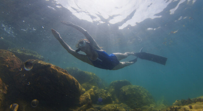 Young slim woman swims underwater, freediving and snorkeling in the sea near the coral reef near the island of Ilha Grande in Brazil