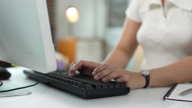 Unrecognizable businesswoman typing on a computer keyboard in the office, female employee working on a project, sending an email and communicating with clients