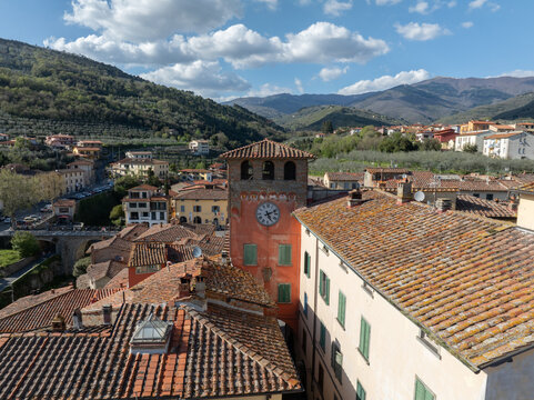 Aerial view of the historic village with its iconic clock tower, terracotta rooftops, and surrounding hills in Loro Ciuffenna, Tuscany, Italy.