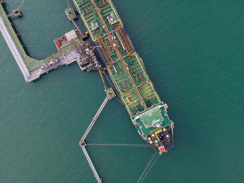 Aerial view of a large oil tanker docked at an industrial terminal in the sea, Cilacap, Central Java, Indonesia.