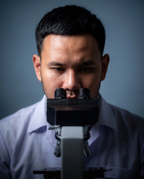 A scientist looking through a microscope, intensely focused on his work.