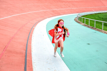 Child in superhero costume running on a colorful track outdoors. © Rawpixel.com