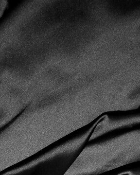 Vertical dark gray silk satin fabric background with copy space and soft folds