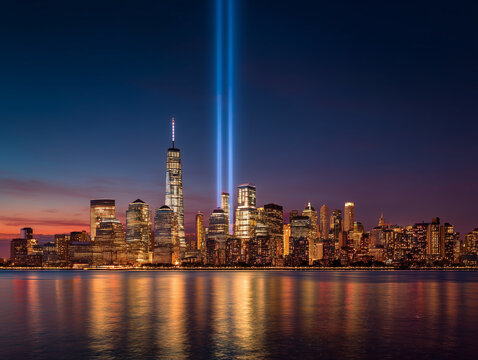 Elegant New York City skyline at twilight transitioning into night, twin memorial beams illuminating the sky, respectful patriotic tribute.