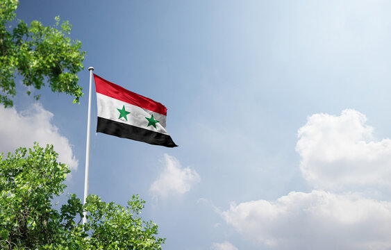 Syria national flag waving in the sky behind the tree. The flag waving in the sky. Syria national flag for independence day.