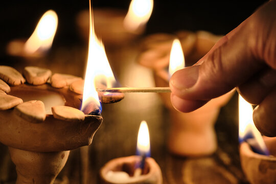 Hand lighting a traditional clay diya during Diwali celebration
