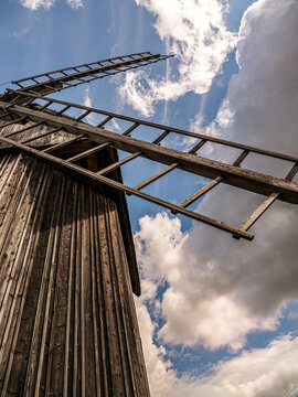 Rustic Wooden Windmill With Sunlit Sails Against A Clear Blue Sky In Countryside