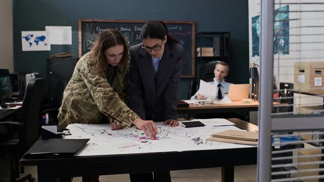 Young adult Caucasian female soldier and civilian advisor analyzing tactical map in military command center. Clip ideal for defense industry marketing and national security training videos