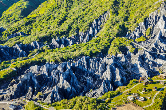 Lush green hills contrast with sharp grey slate rock formations at Moshi Park in Sichuan, China.
