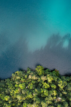 Aerial view of Lake Eacham with its deep turquoise volcanic crater lake water bordered by dense lush rainforest canopy in Atherton Tablelands, Queensland, Australia.