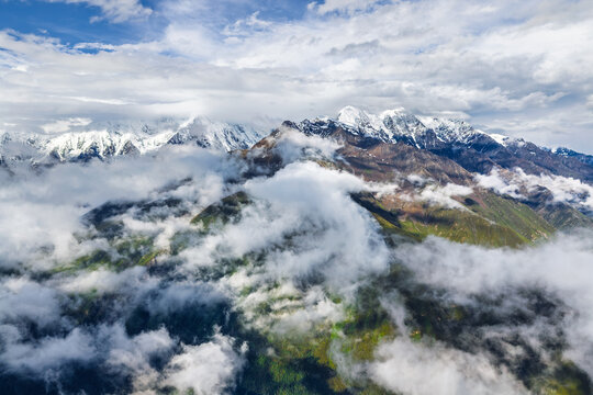 Breathtaking scenery of snow covered mountain range surrounded by clouds in Sichuan, China.