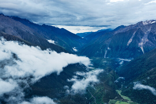 Dramatic aerial perspective of foggy mountain valley covered in thick clouds under overcast sky.