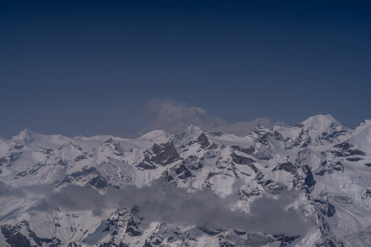 Aerial view of the snow-capped peaks of Nanga Parbat rising above the rugged glaciers and mountain range in Gilgit, Pakistan.
