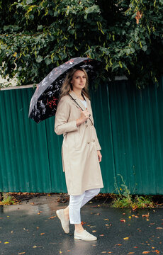 Young woman walking alone with umbrella in autumn rain