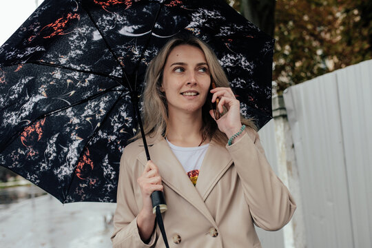 Young woman walking alone with umbrella in autumn rain