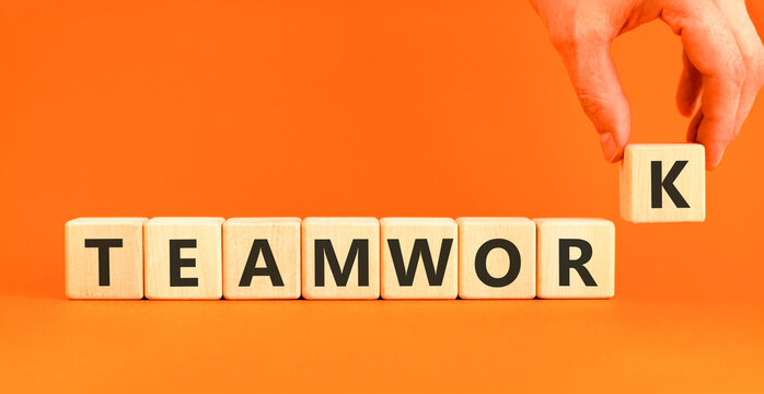 Teamwork word symbol. Concept word Teamwork on beautiful wooden blocks. Beautiful orange background. Businessman's hand. Business support help teamwork word concept. Copy space.