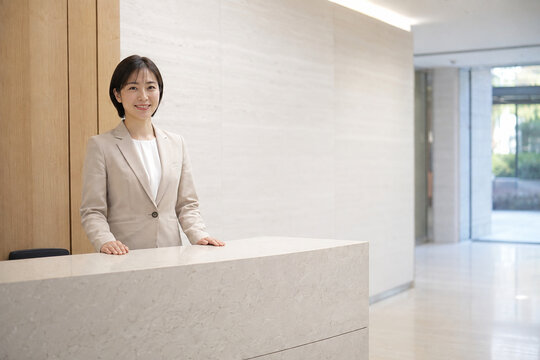 Friendly receptionist in modern corporate lobby with copy space