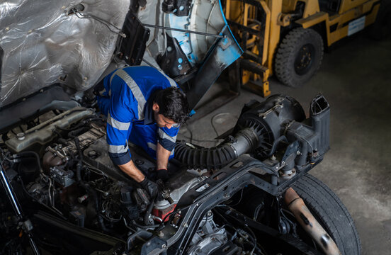 high angle view of professional mechanic in blue uniform inspecting and repairing a heavy duty truck engine in service garage