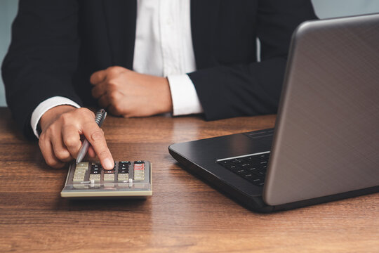 Person using calculator beside laptop at office desk