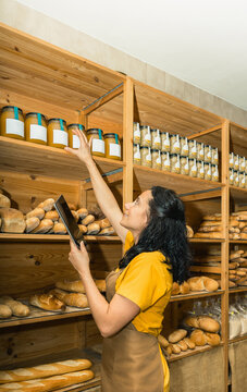 Bakery worker checking inventory with digital tablet
