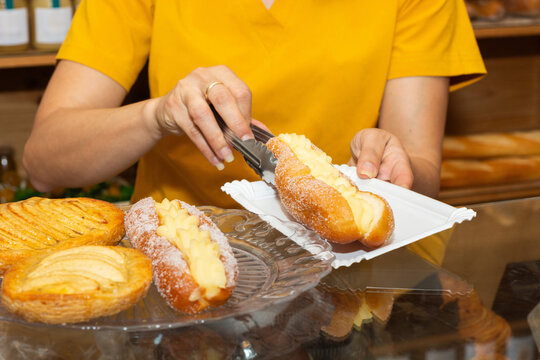 Worker serving cream filled bun in a bakery
