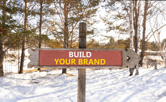 Build your brand words symbol. Concept words Build your brand on beautiful road sign. Beautiful winter forest background. Business and build your brand concept. Copy space.