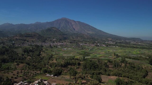 Aerial drone footage of rural village and green vegetable farmland with Mount Panderman background in Pujon, Malang