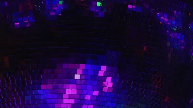 Dazzling display of light plays across mirrored disco ball. Dynamic colors transition from fiery reds and oranges to cool blues and greens, creating energetic atmosphere perfect for late-night party.