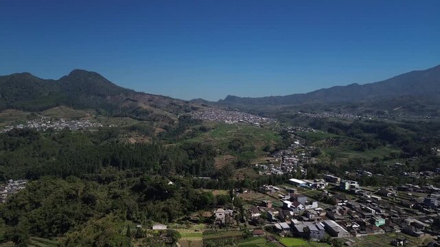 Aerial drone footage of rural village and green vegetable farmland with Mount Panderman background in Pujon, Malang