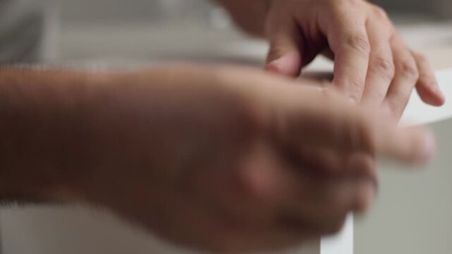 Close up of male hands screwing a bolt with screwdriver to assemble flat pack wooden shelf