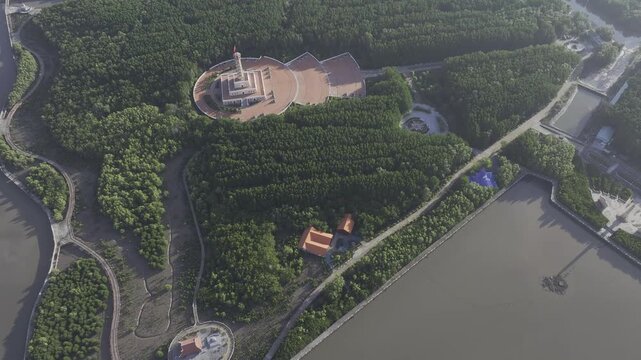 Aerial drone view of Mui Ca Mau National Park in Dat Mui, Ca Mau, Vietnam, featuring the national flagpole and coordinate marker surrounded by sunlit mangrove forests.