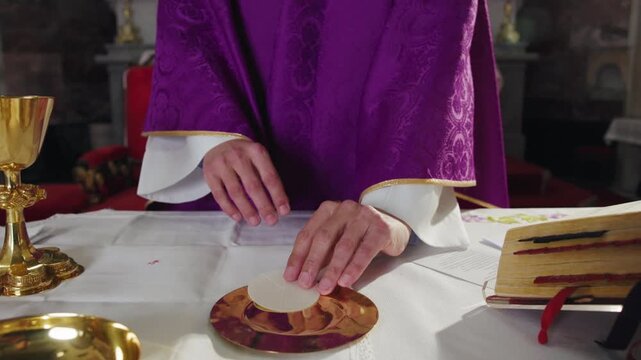 Priest blessing a communion wafer during a service, raising a Eucharistic Host. The ritual act of the elevation during the Catholic Mass.