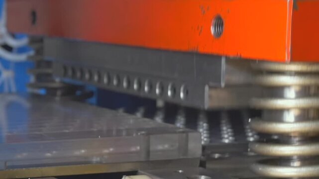 A mechanical arm precisely shapes raw materials on a metallic tray, operating under bright lights during busy daily shifts in a bustling manufacturing workshop.