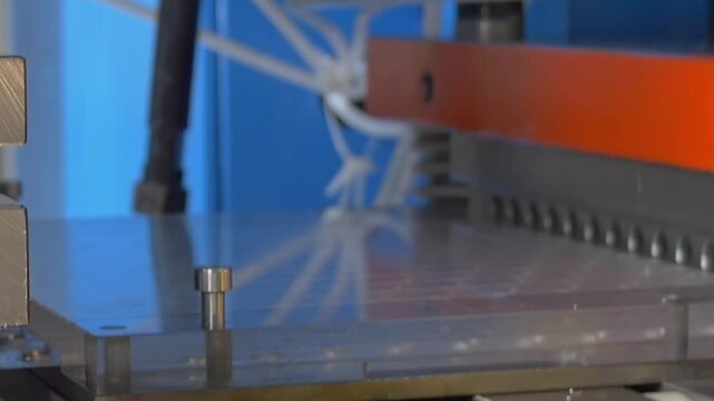 Heavy machinery uses hydraulic pressure to stamp textured industrial designs onto metal sheets, manufacturing high-quality parts through repetitive afternoon production in the workshop.
