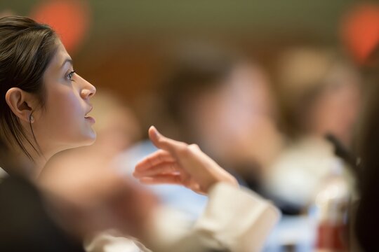 Young woman speaking actively and gesturing with her hand in a conference room setting