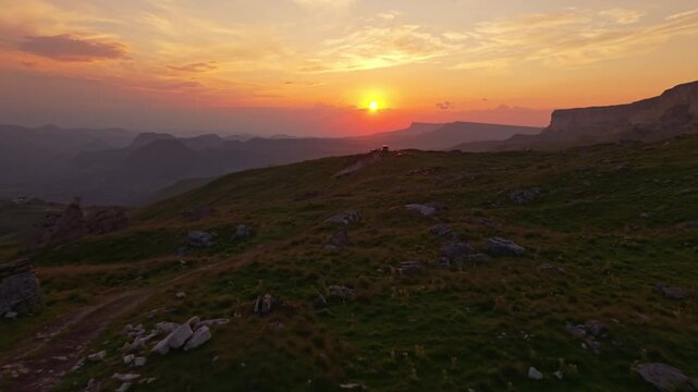 Aerial tracking shot over mountainous landscape at sunset