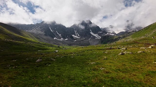 Aerial Forward Movement Over Green Alpine Valley Toward Mountains