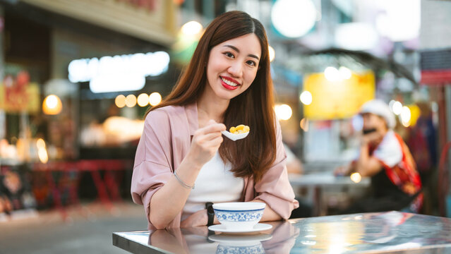 Smiling face traveler woman eating dessert at street food market tasty asia menu tour nightlife in Chinatown Bangkok city
