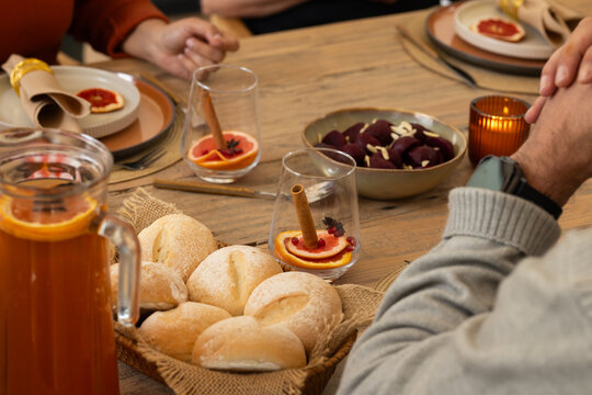 Close friends sitting around wooden dining table sharing seasonal meal with woven bread basket