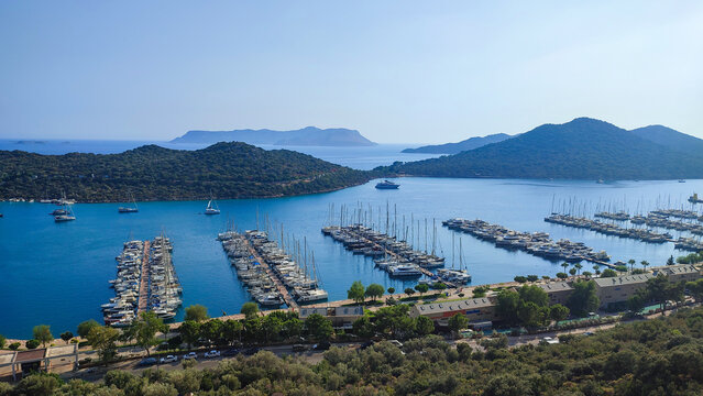 A large marina filled with many yachts and boats in a beautiful blue bay, marine travel, summer vacation, beautiful landscape, coastal view, luxury life. 
