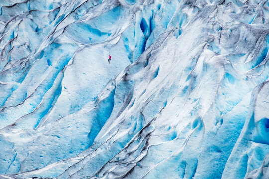 Dramatic winter landscape of a man climbing a glacier, Nigardsbreen, Norway